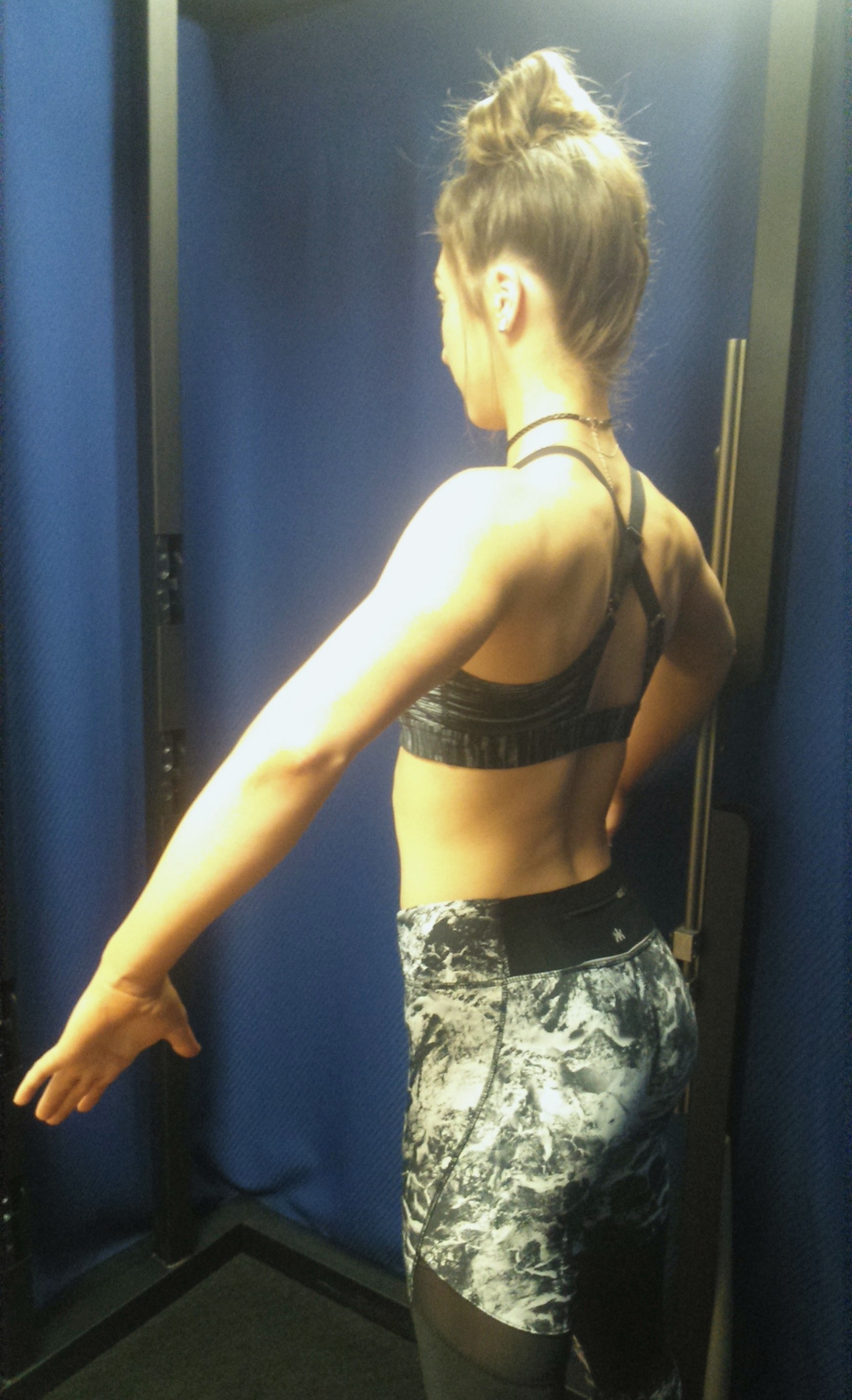 Woman standing inside a 3D body scanning booth.