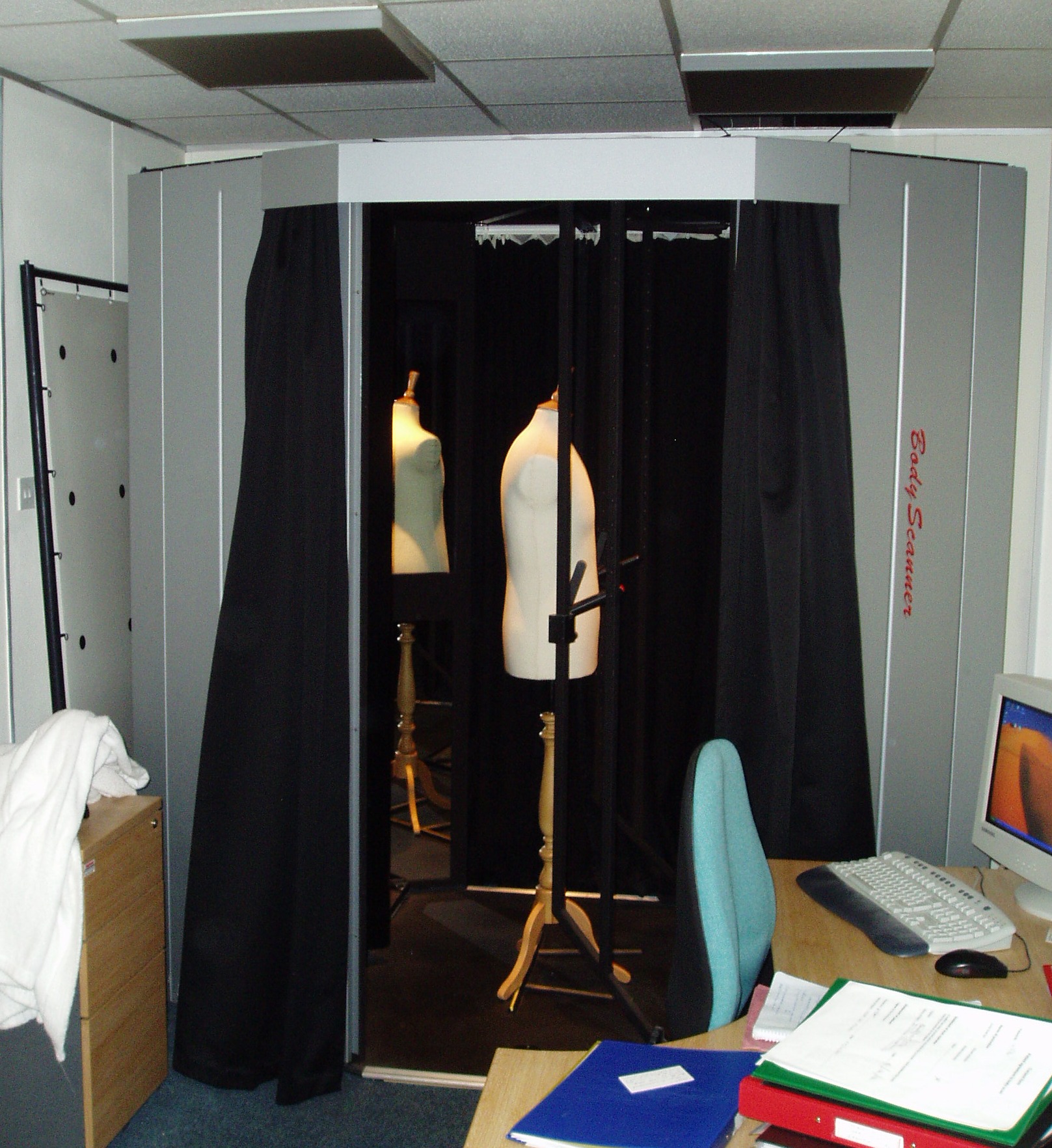 Early Wicks and Wilson body scanning booth with black curtains and dress forms inside.